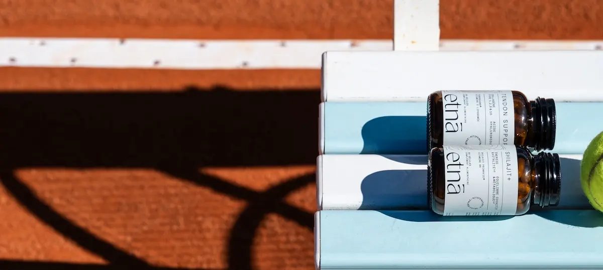 Tendon Support et Shilajit+ sur un banc de court de tennis en terre battue