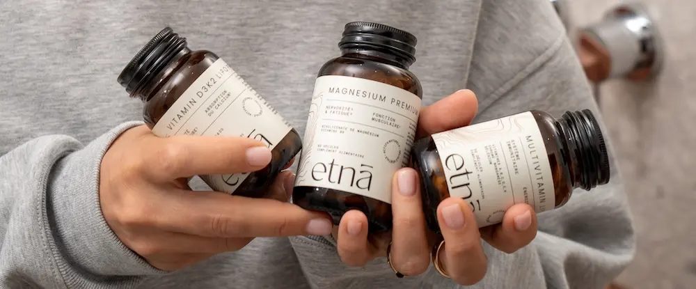 Trois flacons etnā tenus en main : Vitamin D3K2, Magnesium Premium, Multivitamin