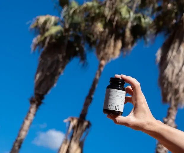 Flacon Vitamin D3K2 tenu sous les palmiers